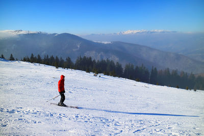 Side view of person skiing on snow covered slope against mountains