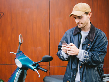 Young man with bicycle standing against wall