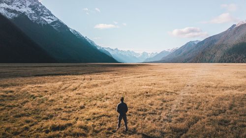 Rear view of man on field against sky