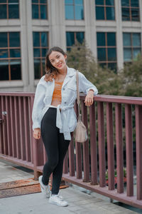 Portrait of young woman standing on bridge