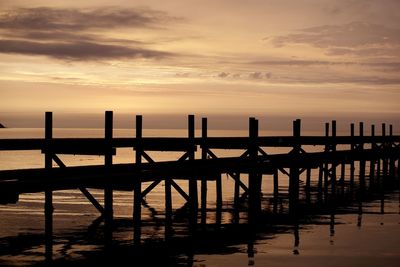 Silhouette structure in sea against cloudy sky