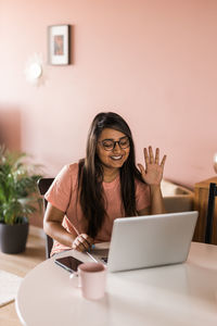 Young woman using mobile phone while sitting at home