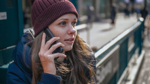 Portrait of young woman using mobile phone in city