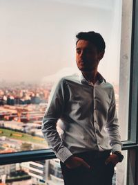 Young man looking away while standing in apartment 