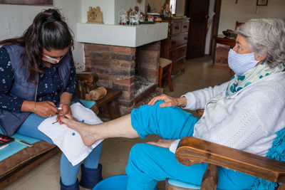 Woman wearing mask doing pedicure to patient