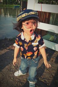 Cute surprised girl looking away while wearing eyeglasses by lake