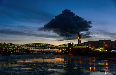 Illuminated bridge over river against sky in city at night