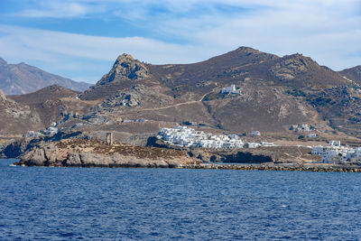 Scenic view of sea by mountains against sky