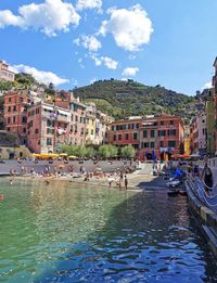 Boats in canal amidst buildings in city against sky
