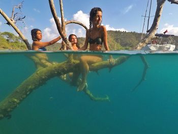 Friends in wearing bikini sitting on branch in tree