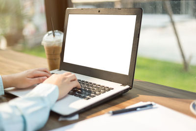 Close-up of businesswoman using laptop on table at sidewalk cafe