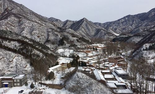 Snow covered village and mountains against sky