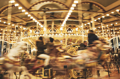 People walking in illuminated carousel at night