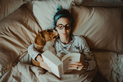 High angle view of young woman lying on bed