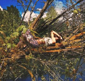 Side view of woman relaxing on tree