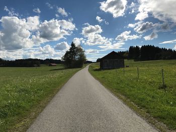 Road amidst field against sky