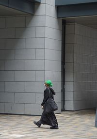 Side view of woman walking against building