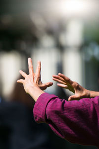 Cropped hand of woman gesturing against blurred background