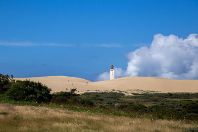 Lighthouse on field against clear blue sky