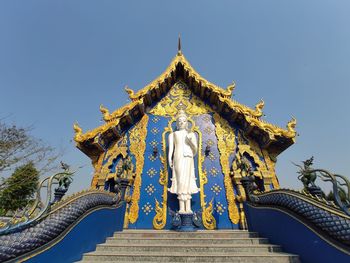 Low angle view of statue against temple building against clear sky