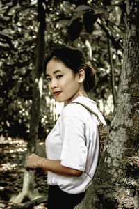 Portrait of woman standing on tree trunk