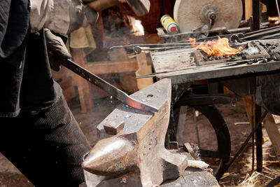 Midsection of blacksmith working at workshop