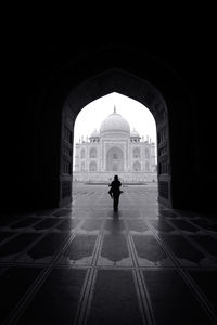 Person standing in arched doorway against taj mahal