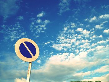 Low angle view of road sign against cloudy sky