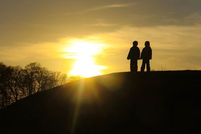 Silhouette men standing against sky during sunset