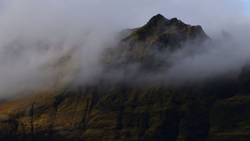 Smoke emitting from mountain against sky