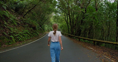Rear view of woman walking on road in forest anaga, tenerife north, canary islands, spain