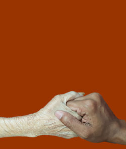 Close-up of hands against orange background