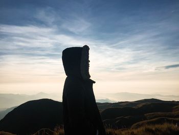 Silhouette of a man behind a scenic view of landscape against sky during sunset