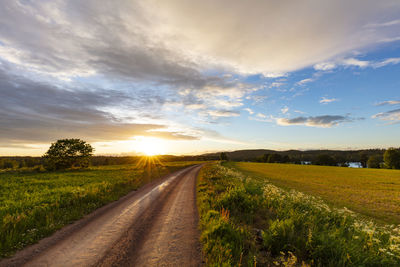 View of rural landscape with dirt track at sunset