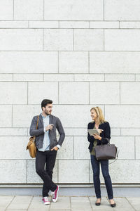 Full length of smiling business people discussing on sidewalk