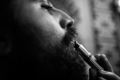 Close-up of bearded young man applying lipstick