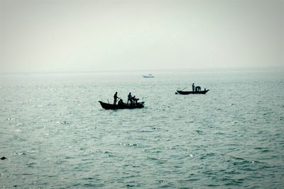 People on boat in sea against sky