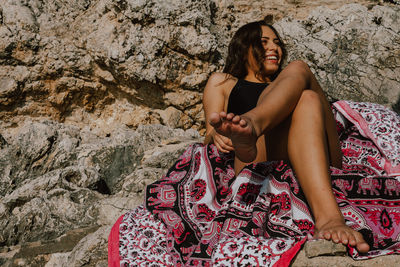 Smiling woman sitting against rock formation