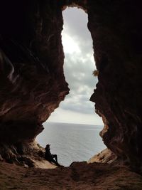 Single person inside a cave with sea and sky view