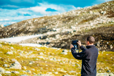 Man photographing against sky