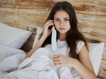 Portrait of young woman relaxing on bed at home