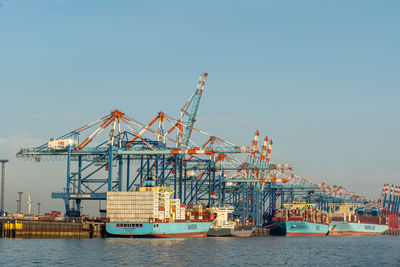 Cranes at commercial dock against clear sky