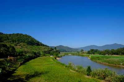 Scenic view of lake and mountains against clear blue sky