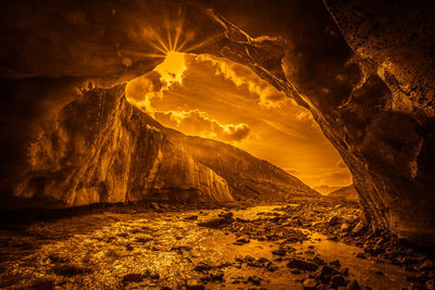 Fantasy orange color effect of glacial stream that coming out of a cave into ice