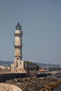 Lighthouse by sea against clear sky