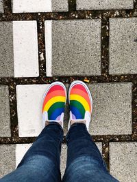 Low section of woman in colorful shoes standing on footpath