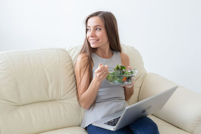 Young woman using phone while sitting on sofa