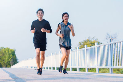 Full length of young couple on railing against sky