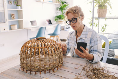 Portrait of young woman using digital tablet while sitting on table