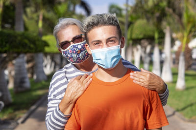 Portrait of grandmother and grandson wearing mask standing outdoors